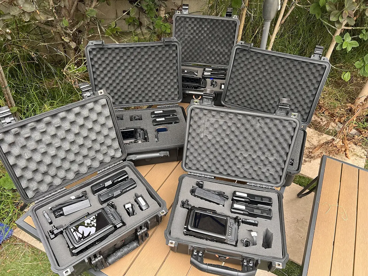 Five Tinseltown kit cases open on a deck, each packed with a camera, batteries and cables